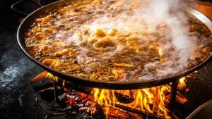 paella being cooked in a wood fired pit